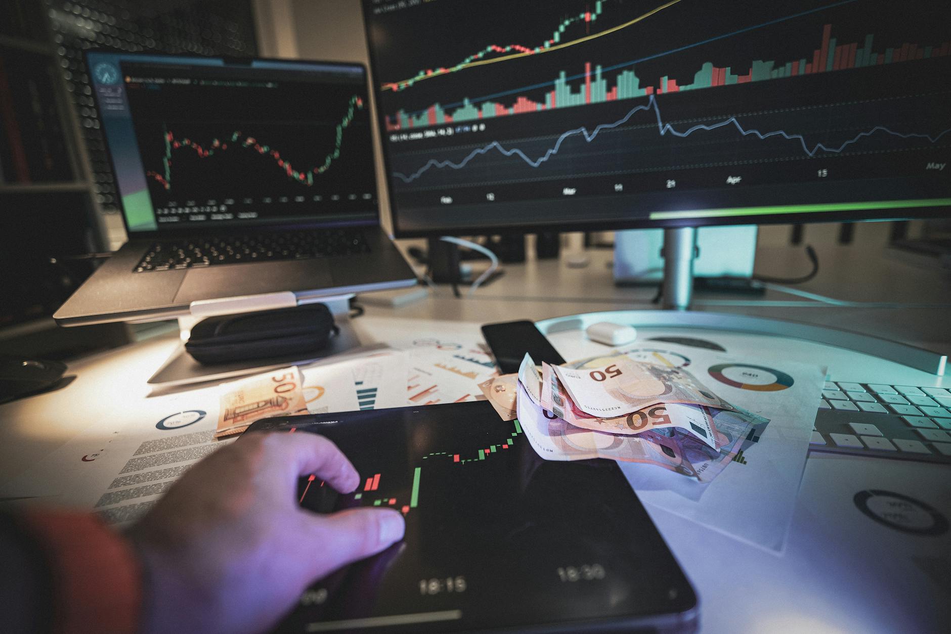 hand on tablet displaying stock quotes euro cash currency